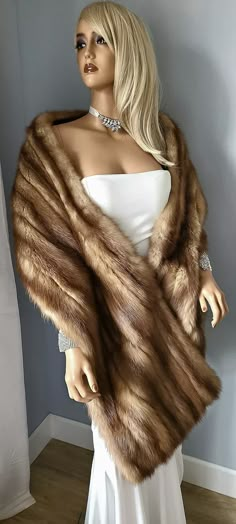 a mannequin is dressed in a white dress and brown fur stole with jewels on it