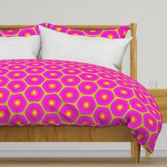 a bed with pink, yellow and orange bedspread on top of wooden headboard