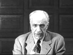 an old man in a suit and tie sitting at a table