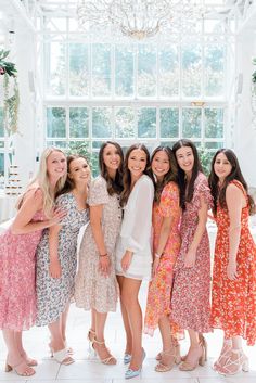 a group of women standing next to each other in front of a chandelier