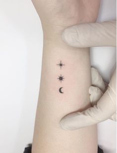 a woman's arm with three stars and a moon tattoo on it