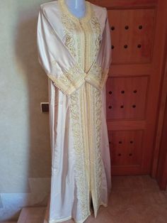 This incredible Vintage light brown Moroccan wedding kaftan dress for women was made in Morocco Made in Morocco Embroidery: handwoven by Moroccan women Fabric: brown silk Embroidery: gold pattern with pearls ❤️❤️ Size and Measurements: Shoulder: 37 cm / 14.5 in Length: 150 cm / 59 in Chest: 54 cm / 21 in Length of sleeves: 47 cm / 18.5 in Width of sleeves: 16 cm / 6 in Hip: 63 cm / 24.8 in Condition: used, Excellent condition, ready to be wearing ❤️ Occasions: Can be used for maternity dress, ba Traditional Gold Embroidered Gown, Gold Dresses With Pearl Embroidery In Traditional Drape, Gold Dress With Pearl Embroidery And Traditional Drape, Traditional Gold Embroidered Dress For Wedding, Eid Embellished Gold Gown, Gold Embellished Gown For Eid, Festive Ceremonial Gold Gown, Traditional Gold Embroidered Wedding Dress, Elegant Gold Dress With Resham Embroidery