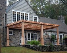 a house with stone walls and wooden pergols