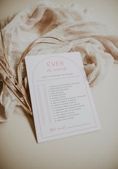 a white paper with pink writing sitting on top of a table next to a piece of cloth