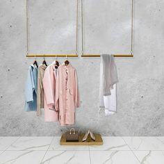 three clothes hanging on hooks in front of a white wall with marble floor and gold frame