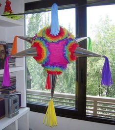 a colorful kite hanging from the ceiling in front of a window with bookshelves