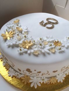 there is a white cake with gold flowers on it, and the number five spelled out