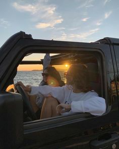 two people sitting in the passenger seat of a truck with the sun setting behind them