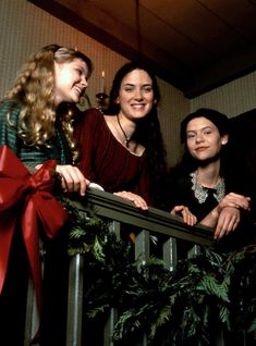 four young women standing on a balcony with red ribbon around their necks and smiling at the camera