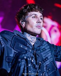 a man with tattoos and piercings on his head standing in front of a microphone