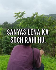 a man sitting on top of a lush green field next to a forest filled with trees