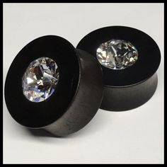 pair of black acrylic ear plugs with clear crystal stone in center on white background