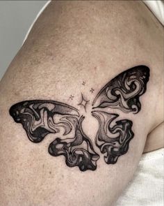 a black and white butterfly tattoo on the back of a man's shoulder