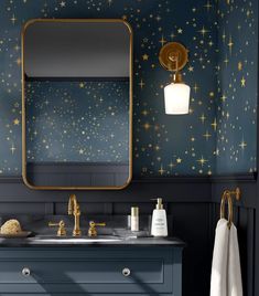 a blue bathroom with gold stars on the wall and a large mirror over the sink