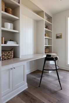 a white desk and shelves in a room with hardwood floors, wood flooring and open shelving