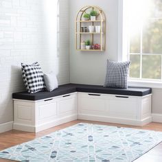 a window seat with pillows on it in front of a white brick wall and wooden floor