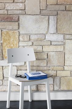 a white chair with a book on it in front of a wall made of bricks