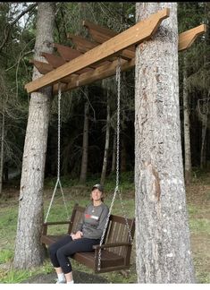 a woman sitting on a swing in the woods