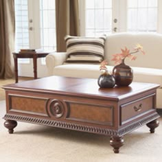 a coffee table with two vases on it in front of a couch and window