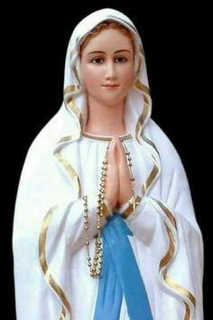 a statue of the virgin mary holding a blue ribbon and wearing a white robe with gold trim