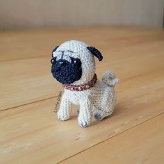 a small crocheted pug dog sitting on top of a wooden table