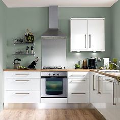 a kitchen with green walls and white cabinets is featured in the uk's number one kitchen retailer