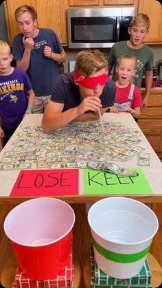 a group of kids standing around a table with money on it and two buckets in front of them