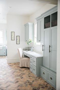 a kitchen with gray cabinets and white counter tops, along with a dining room table