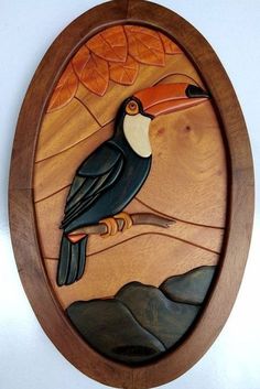 a wooden wall hanging with a toucan bird on it's side and leaves in the background