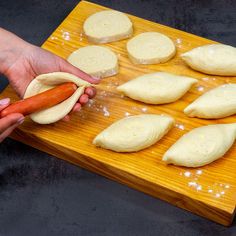 a person holding a hot dog bun in front of some doughnuts on a cutting board