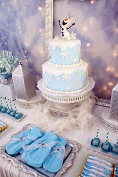 a table topped with blue and white cakes covered in frosted icing next to other desserts