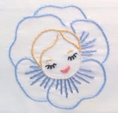 a close up of a flower with a face on it's center piece, embroidered onto a white shirt