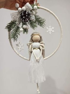 a hand holding a christmas ornament in the shape of a hoop with snowflakes and pine cones