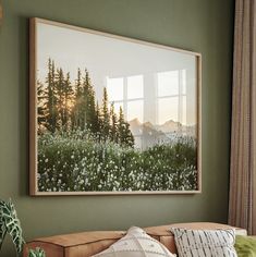 a living room with green walls and a painting on the wall above a couch in front of a window