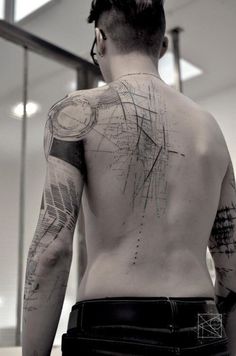 a man with tattoos on his back standing in front of a mirror