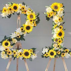 sunflowers and daisies are arranged in the shape of the letter e on a easel