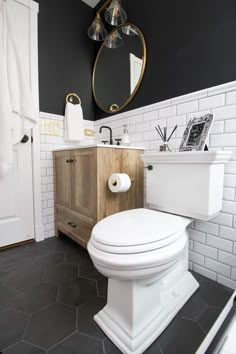 a white toilet sitting in a bathroom next to a wooden cabinet and sink with a mirror above it