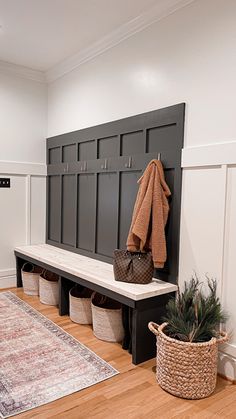 an entryway with a bench, coat rack and baskets on the floor next to it