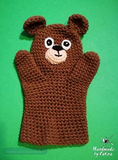 a crocheted brown bear mitt on a green background