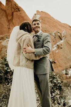 a bride and groom embracing each other in front of some mountains with snow on them