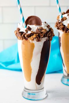 two glasses filled with ice cream and chocolate covered desserts on top of a table