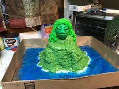 a cake in the shape of a woman's head with green hair and eyes