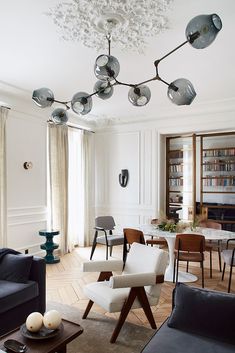 a living room filled with furniture and a chandelier hanging from the ceiling in front of a window