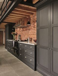 a kitchen with black cabinets and brick walls