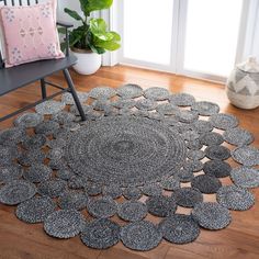 the rug is on the wooden floor in front of a chair and potted plant