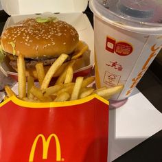 a mcdonald's hamburger and fries are on the table next to a cup of soda