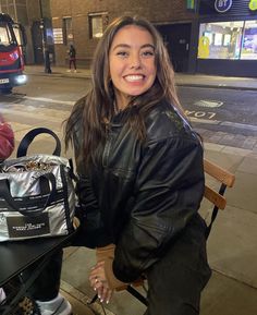 a woman sitting at a table with a purse on her lap, smiling for the camera