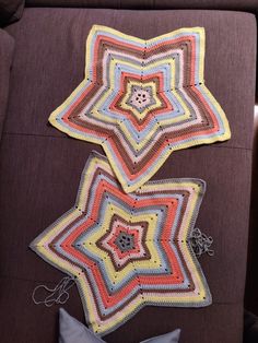 two crocheted stars sitting on top of a brown couch next to a pillow