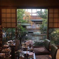 a dining room table is set with place settings and flowers in front of the window