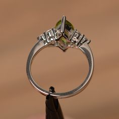 It is a natural peridot ring. The main stone is 6mm*12mm marquise cut, weight about 1.55 carats. The basic metal is sterling silver and plated with rhodium. To change the metal to a solid gold (white/rose) or platinum is also available, please ask for a quotation if you want. You can also go to my shop Home for more elegant rings: https://www.etsy.com/shop/godjewelry?ref=hdr_shop_menu More peridot rings: https://www.etsy.com/shop/godjewelry?section_id=20709252 Customization is always welcome and Green Marquise Diamond Promise Ring, Green Marquise Cut Birthstone Jewelry, Green Marquise Rings With Accent Stones, Green Marquise Cut Promise Ring, Marquise Cut Diamond Ring For May Birthstone, Green Gemstone Ring With Marquise Cut, Green Marquise Cut Gemstone Ring, Green Marquise Cut Ring With Center Stone, Green Marquise Cut Diamond Ring With Center Stone